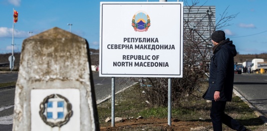 Ένας άνδρας περπατά μπροστά από μια πινακίδα που γράφει «Δημοκρατία της Βόρειας Μακεδονίας», στα σύνορα Μακεδονίας-Ελλάδας κοντά στη Γευγελή, στις 13 Φεβρουαρίου 2019. [Robert ATANASOVSKI/AFP]