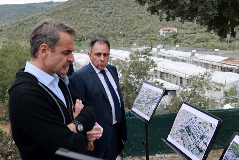 Ο Κυριάκος Μητσοτάκης κοιτάζει φωτογραφίες του πρώην Κέντρου Υποδοχής και Ταυτοποίησης Προσφύγων (ΚΥΤ) της Μόριας, κοντά στο χωριό Μόρια της Λέσβου, στις 12 Μαΐου 2023. [Manolis Lagoutaris/AFP]