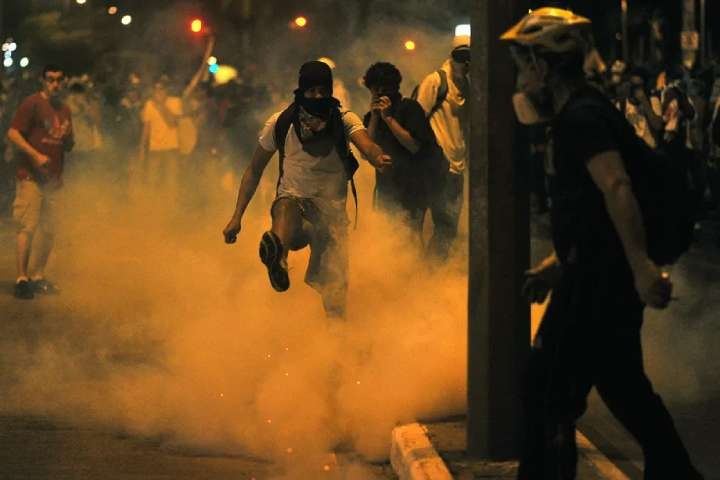 A demonstrator kicks a tear gas shell during clashes with the police outside the Mineirao stadium in Belo Horizonte, on June 26, 2013.