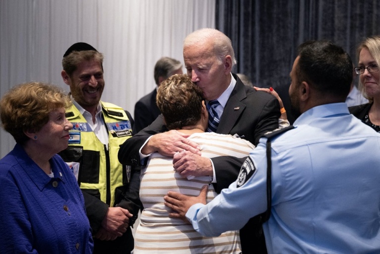Ο αστυνομικός Εβιάταρ Έντρι κοιτάζει, καθώς ο πρόεδρος των ΗΠΑ Τζο Μπάιντεν αγκαλιάζει τη μητέρα του Ρέιτσελ Έντρι, η οποία κρατήθηκε όμηρος από τη Χαμάς, στις 18 Οκτωβρίου 2023, στο Τελ Αβίβ. [Brendan Smialowski/AFP]