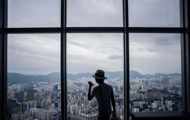 A visitor takes photos of the Kowloon district from the viewing deck of the International Commerce Centre (ICC) in Hong Kong, 2017.