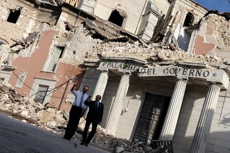 Ο τότε πρωθυπουργός της Ιταλίας Σίλβιο Μπερλουσκόνι και ο τότε πρόεδρος των ΗΠΑ Μπαράκ Ομπάμα κοιτάζουν το Palazzo del Governo, που καταστράφηκε από σεισμό τον Απρίλιο του 2009 στο κέντρο της πόλης Λ'Ακουίλα, κατά τη διάρκεια της συνόδου κορυφής της G8, στις 8 Ιουλίου 2009. [Joe Klamar/AFP]