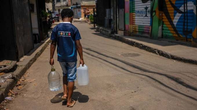 A resident of Rocinha carrying water collected from a natural spring during a heat wave in Rio de Janeiro, Brazil, on November 17, 2023.