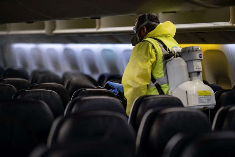 Ένα μέλος του προσωπικού του αεροδρομίου Σαρλ ντε Γκωλ απολυμαίνει το εσωτερικό ενός αεροσκάφους της Air France στις 14 Μαΐου 2020, καθώς η Γαλλία χαλαρώνει τα μέτρα που είχε λάβει για τον περιορισμό της εξάπλωσης του COVID-19. [Ian LANGSDON/EPA POOL/AFP]