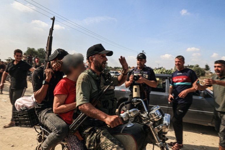 Παλαιστίνιοι μαχητές μεταφέρουν με μοτοσικλέτα μια Ισραηλινή γυναίκα φερόμενη ως αιχμάλωτη, στο Χαν Γιουνίς στη νότια Λωρίδα της Γάζας, στις 7 Οκτωβρίου 2023. [AFP]