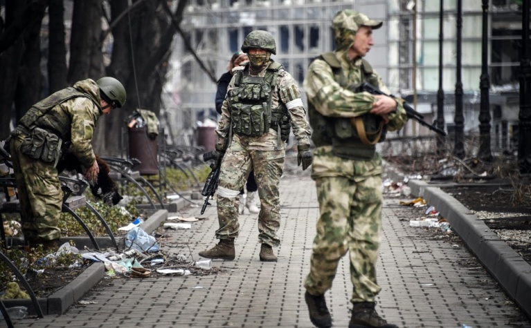 Ρώσοι στρατιώτες περπατούν κατά μήκος ενός δρόμου στη Μαριούπολη στις 12 Απριλίου 2022, τις ημέρες που εντεινόταν η εκστρατεία για την κατάληψη του στρατηγικού λιμανιού. [Alexander NEMENOV/AFP]