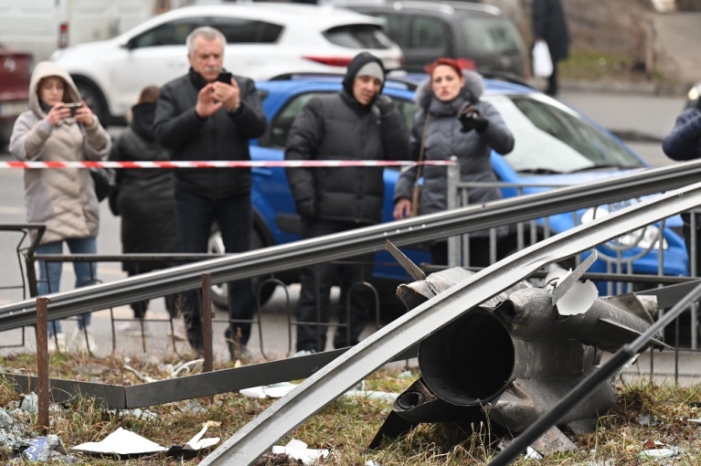 Ουκρανοί στέκονται κοντά στα υπολείμματα μιας οβίδας στο Κίεβο στις 24 Φεβρουαρίου 2022, ημέρα που ο Ρώσος πρόεδρος Βλαντιμίρ Πούτιν ανακοίνωσε την έναρξη της στρατιωτικήςς επιχείρησης στην Ουκρανία. [Sergei SUPINSKY / AFP]
