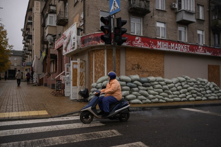 Μια γυναίκα οδηγεί ένα σκούτερ μπροστά από σφραγισμένα παράθυρα στη Ντρουζκίβκα, στην περιοχή του Ντόνετσκ, στην ανατολική Ουκρανία, στις 10 Οκτωβρίου 2025, εν μέσω της ρωσικής εισβολής στην Ουκρανία. [Ed JONES / AFP]
