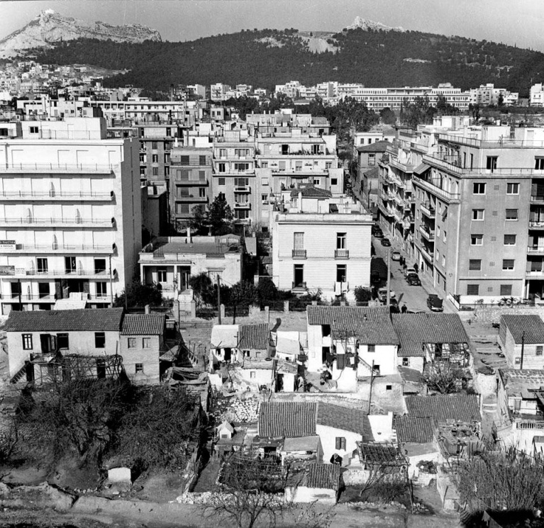 Ο οικισμός Ιλισού, με φόντο τις νεόδμητες πολυκατοικίες που τον περικύκλωναν στη δεκαετία του '60, λίγο πριν την κατεδάφισή του. [Εικόνες από το άρθρο "Ο Αυτόνομος Συνοικισμός του Ιλισσού στην Αθήνα" του Δημήτρη Φιλιππίδη, δημοσιευμένο στο βιβλίο "Settlem 1.jpg