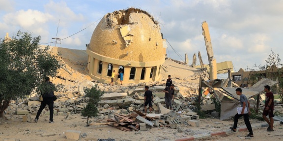 Παλαιστίνιοι περπατούν στα ερείπια ενός τζαμιού που καταστράφηκε από τις ισραηλινές αεροπορικές επιδρομές στο Χαν Γιουνίς, στη νότια Λωρίδα της Γάζας, στις 8 Οκτωβρίου 2023. [SAID KHATIB/AFP]
