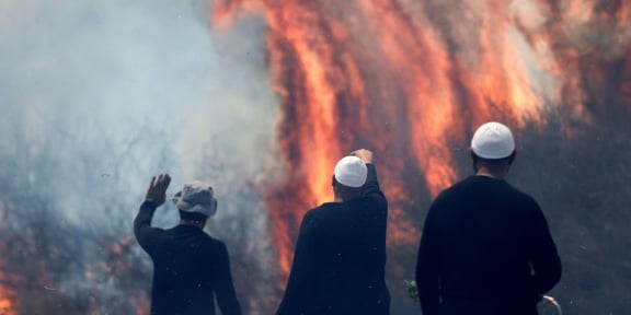 Τοπικοί άνδρες Δρούζοι παρακολουθούν τις φλόγες που καίνε ένα χωράφι μετά την εκτόξευση ρουκετών από το νότιο Λίβανο που προσγειώθηκαν στα προσαρτημένα στο Ισραήλ Υψίπεδα του Γκολάν στις 9 Ιουνίου 2024, εν μέσω των συνεχιζόμενων διασυνοριακών συγκρούσεων μεταξύ ισραηλινών στρατευμάτων και μαχητών της Χεζμπολάχ. [Jalaa MAREY / AFP]