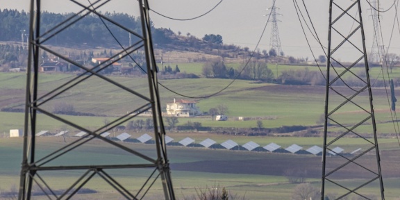 Ηλεκτρικοί πυλώνες υψηλής τάσης κοντά στην πόλη της Θεσσαλονίκης που παρέχουν ενέργεια από λιγνιτικούς σταθμούς στην περιοχή της Πτολεμαΐδας και της Κοζάνης, με κάποιους ηλιακούς συλλέκτες στο βάθος. [Νικόλας Οικονόμου/NurPhoto]