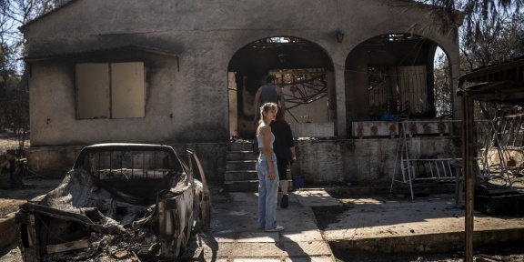 Ιδιοκτήτες εξετάζουν τις ζημιές στο καμένο σπίτι τους μετά από πυρκαγιά που έπληξε τα βορειοανατολικά προάστια της Αθήνας, στο Χαλάνδρι, στις 13 Αυγούστου 2024. [Angelos Tzortzinis/AFP]