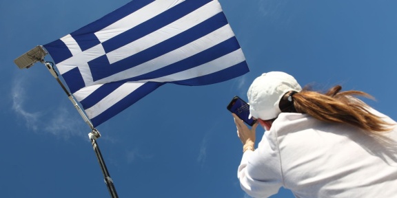 Γυναίκα φωτογραφίζει σημαία μεγάλων διαστάσεων που υψώθηκε στον Φλοίσβο του Παλαιού Φαλήρου για την παρέλαση της 28ης Οκτωβρίου, το 2024. [Γιάννης Παναγόπουλος/Eurokinissi]