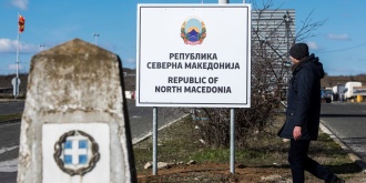 Ένας άνδρας περπατά μπροστά από μια πινακίδα που γράφει «Δημοκρατία της Βόρειας Μακεδονίας», στα σύνορα Μακεδονίας-Ελλάδας κοντά στη Γευγελή, στις 13 Φεβρουαρίου 2019. [Robert ATANASOVSKI/AFP]